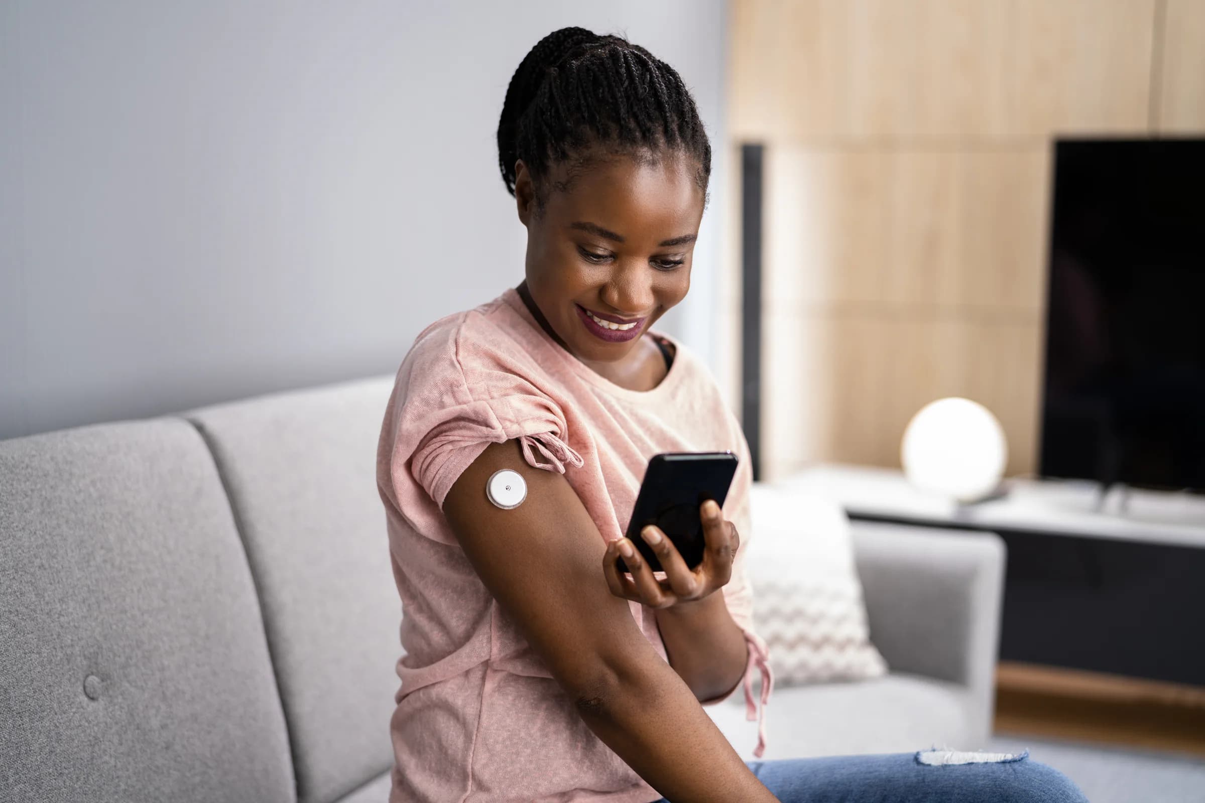 Woman wearing a continuous glucose monitor and checking her phone