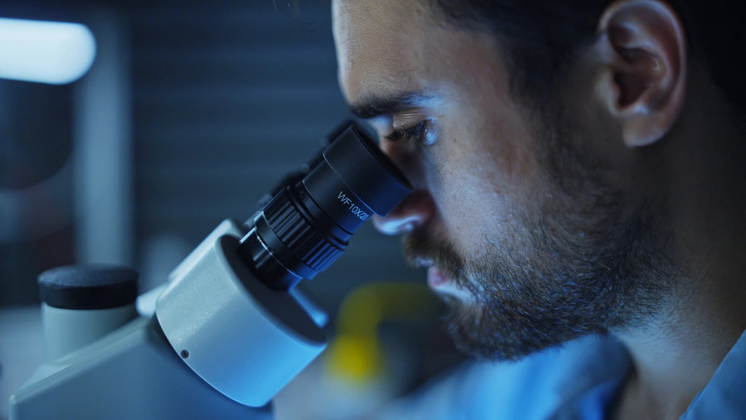 Technician examining a component through a microscope during quality inspection