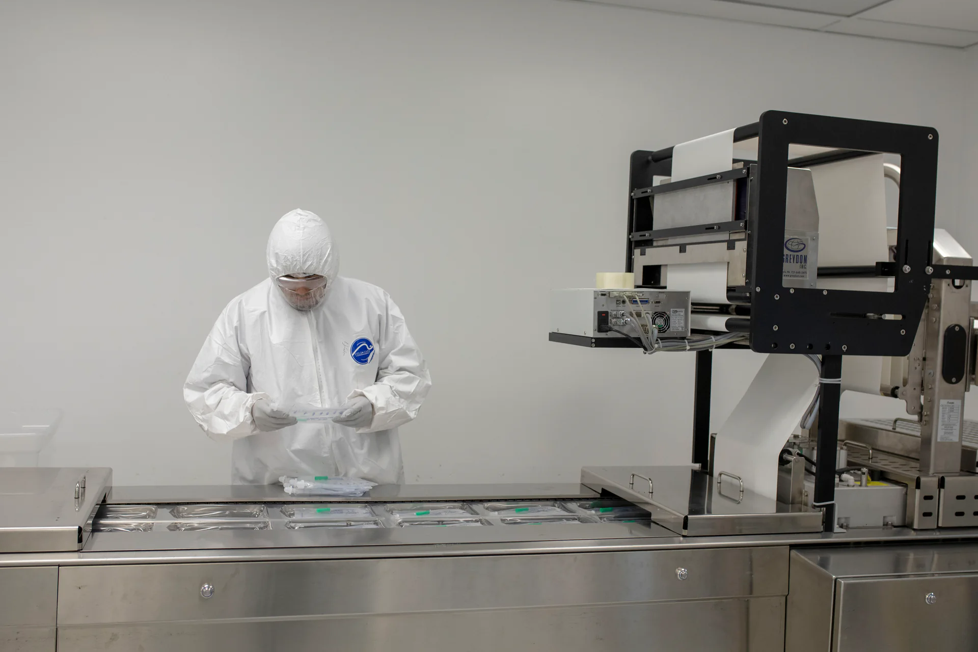 Production operator working beside a form-fill-seal packaging machine