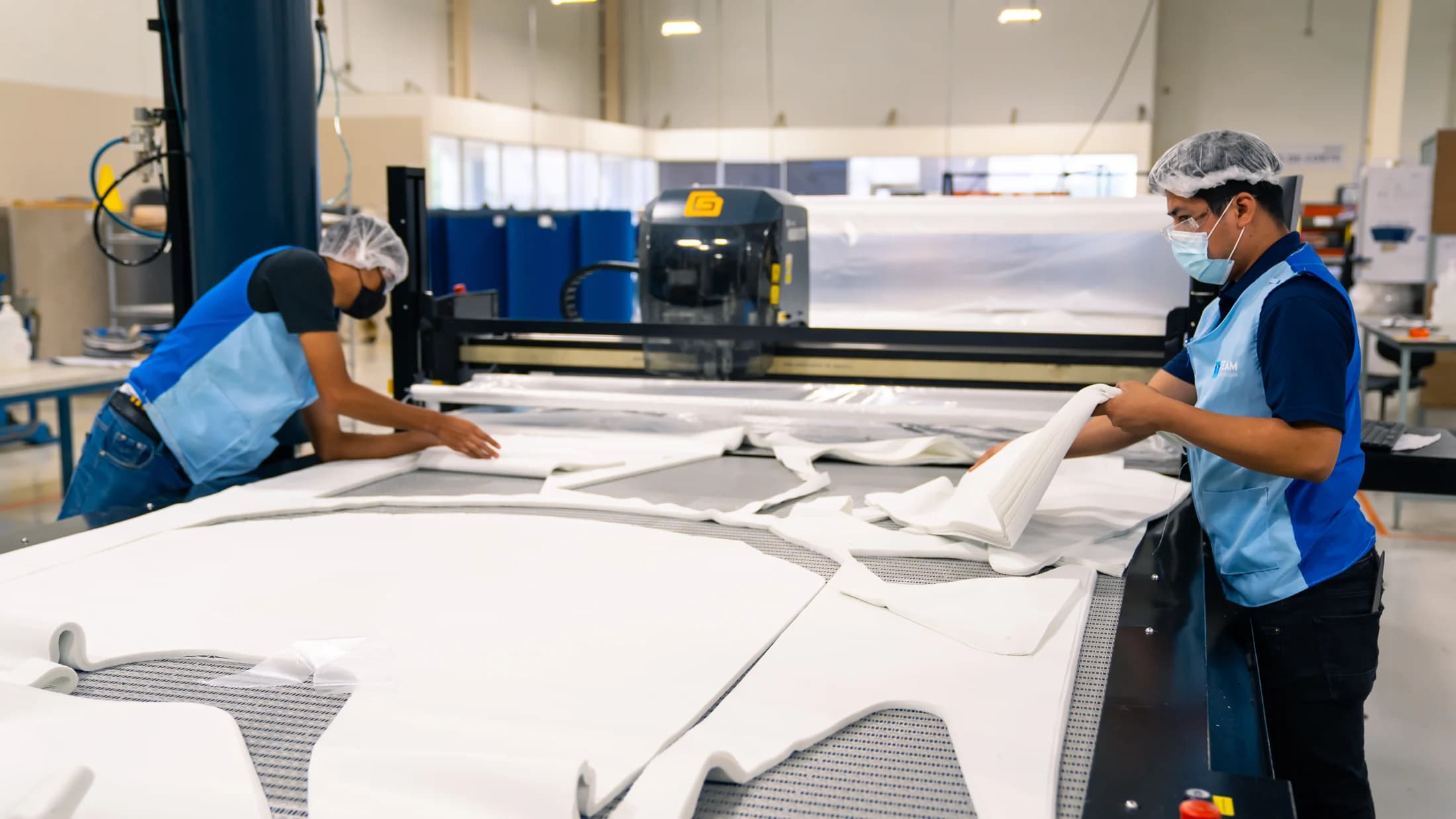 Operators positioning textile material on a large cutting table.